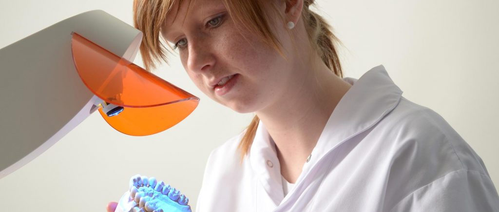 Eine junge Zahntechnikerin fertigt konzentriert hochwertigen Zahnersatz bei Zahntechnik Rißmann.